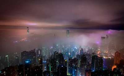 an image of the Hong Kong skyline at night, surrounded by clouds