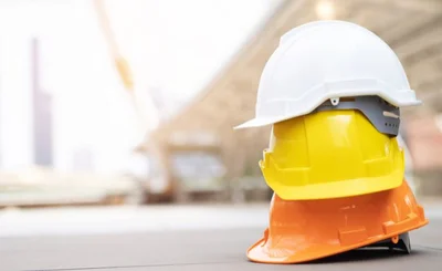 Stack of white, yellow and orange hard hats