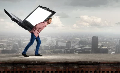 Young man carrying big laptop on back against cityscape © Sergey Nivens - Fotolia.com