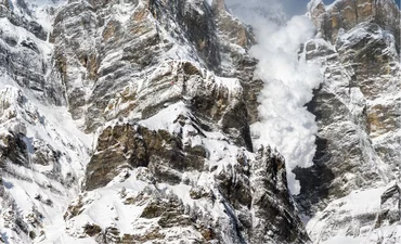 Snow avalanche falling down a rocky mountain