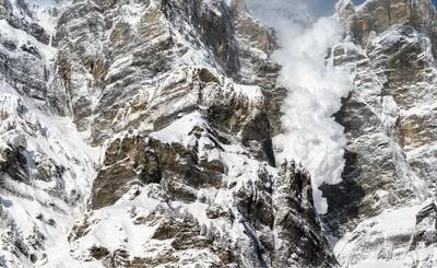Snow avalanche falling down a rocky mountain