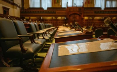 Row of empty seats in government chamber with desks and microphones
