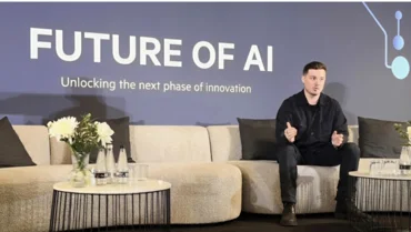 Matt Kempson sat on couch at event. 'Future of AI' is on a screen in the background