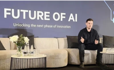 Matt Kempson sat on couch at event. 'Future of AI' is on a screen in the background