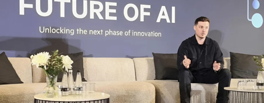 Matt Kempson sat on couch at event. 'Future of AI' is on a screen in the background
