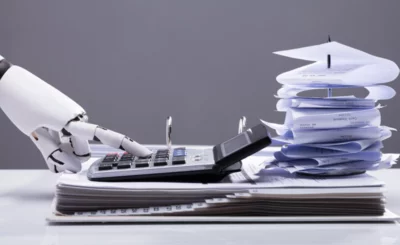 Close-up Of A Robotic Hand Calculating Bills Using Calculator In Office AI finance accounting concept © Andrey_popov - Shutterstock