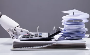 Close-up Of A Robotic Hand Calculating Bills Using Calculator In Office AI finance accounting concept © Andrey_popov - Shutterstock