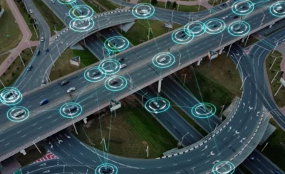 Aerial view: Self-driving autonomous electric cars of the future with HUD elements move along a busy traffic intersection. Concept: Artificial Intelligence, Car Scan, GPS Tracking, Smart Roads, IoT © AIInStock - Shutterstock