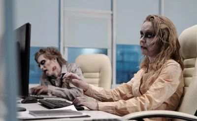 Two zombies sat in front of computers 