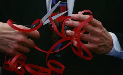 Person in suit and tie in background, with hands wrapped in red tape