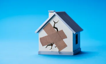 Animated house with bandage over crack in the wall, against a blue background.